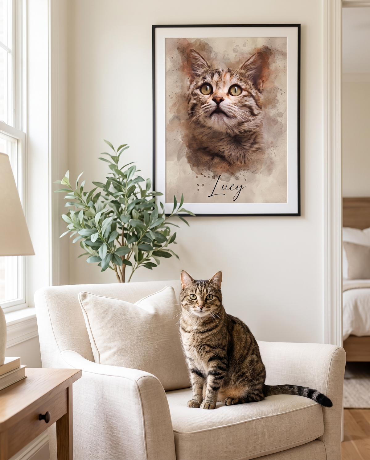 A tabby cat on an armchair beneath a framed watercolor-style portrait of the same cat